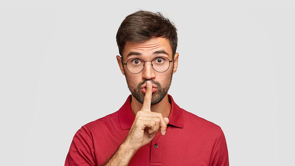 Man tells a secret and holds his finger to his mouth